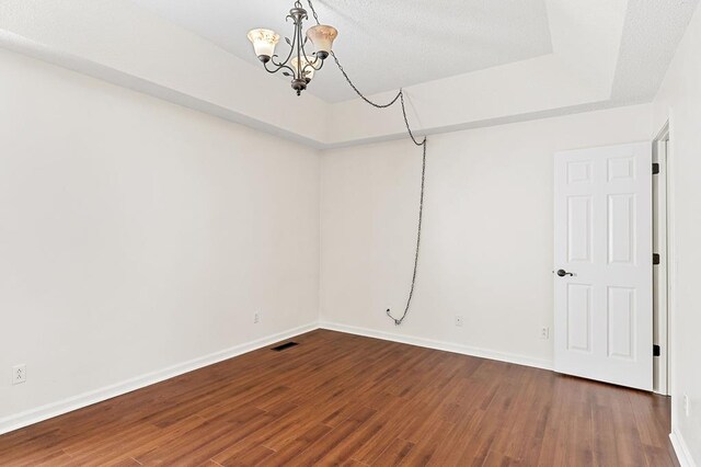 unfurnished room featuring baseboards, visible vents, a chandelier, and dark wood-style flooring