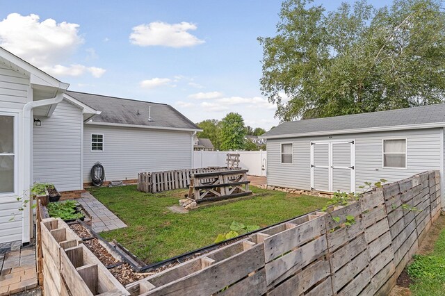 view of yard featuring an outbuilding, a fenced backyard, and a vegetable garden