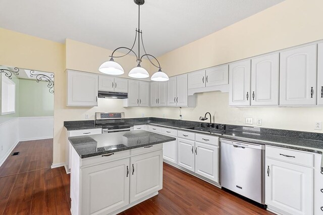 kitchen featuring under cabinet range hood, stainless steel appliances, a sink, white cabinetry, and pendant lighting