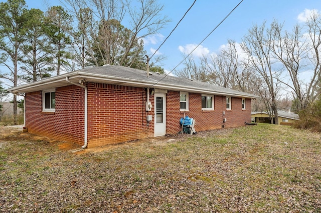 back of property featuring a yard and brick siding