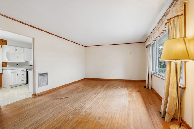 unfurnished living room with heating unit, light wood-style flooring, ornamental molding, and baseboards