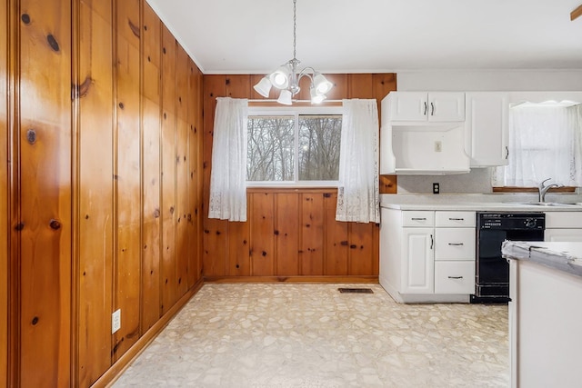 kitchen featuring black dishwasher, light countertops, a sink, and wooden walls