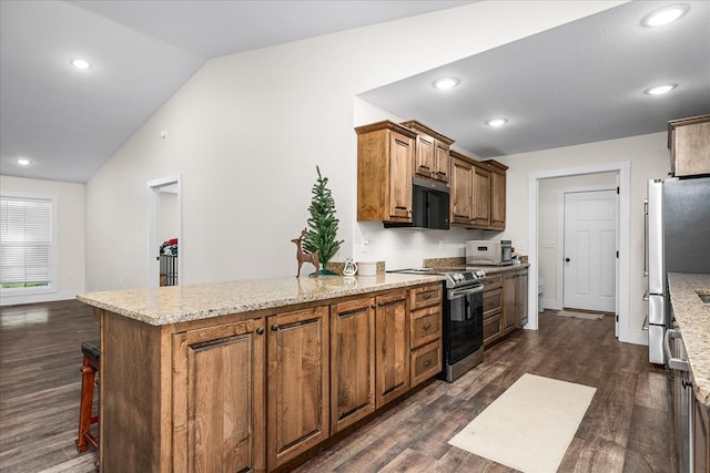 kitchen with brown cabinets, vaulted ceiling, light stone counters, and stainless steel appliances