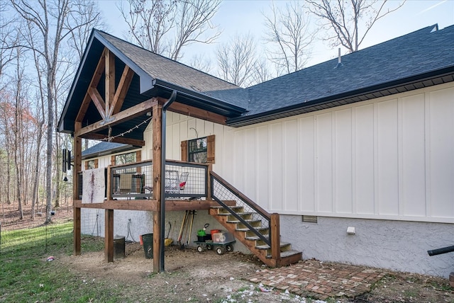 exterior space with board and batten siding, crawl space, roof with shingles, and stairs