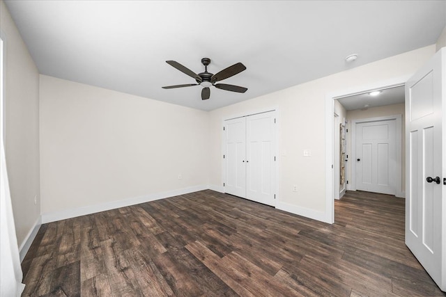 unfurnished bedroom with a ceiling fan, baseboards, dark wood finished floors, and a closet