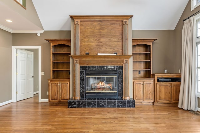 unfurnished living room with a high end fireplace, vaulted ceiling, and light wood finished floors