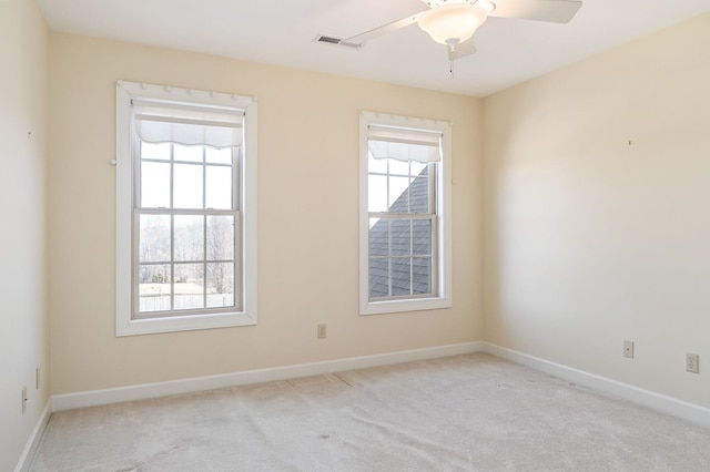 unfurnished room featuring plenty of natural light, visible vents, a ceiling fan, and light colored carpet