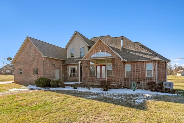 view of front of property with brick siding, a front yard, cooling unit, and french doors