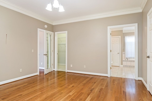 unfurnished bedroom with light wood-style floors, baseboards, a walk in closet, and crown molding