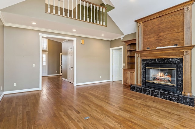 unfurnished living room featuring a premium fireplace, baseboards, crown molding, and wood finished floors