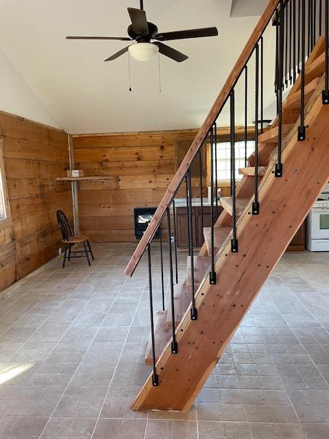 staircase with ceiling fan and wood walls