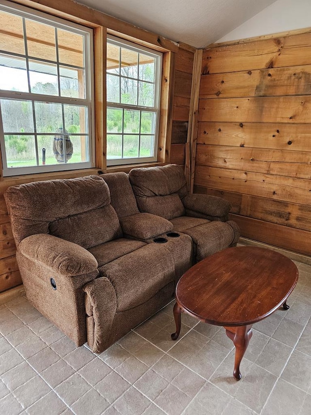 living room featuring lofted ceiling, wood walls, and light tile patterned floors