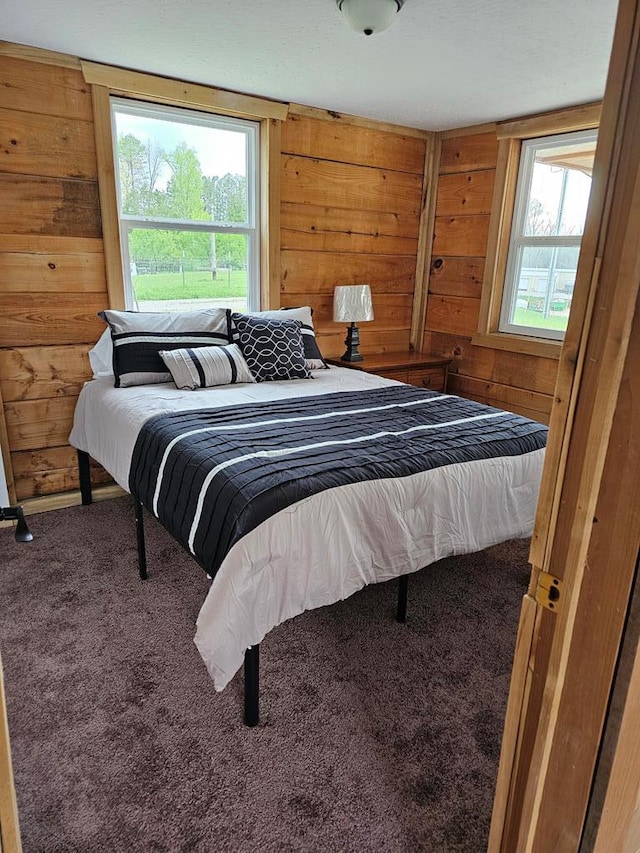 carpeted bedroom featuring wooden walls and multiple windows