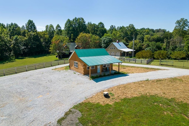 exterior space featuring a yard, metal roof, fence, a rural view, and driveway