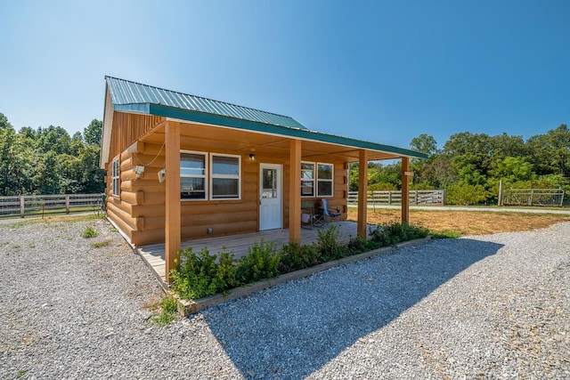 view of front of property with metal roof, log exterior, and fence