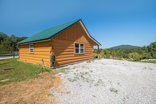 view of outbuilding featuring gravel driveway, fence, and a mountain view