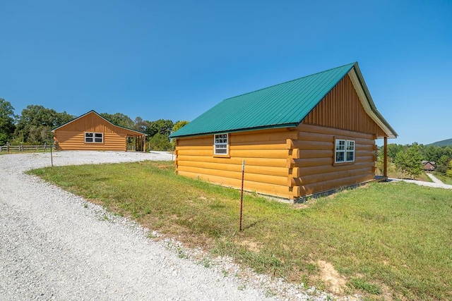 view of side of home featuring metal roof, a lawn, an outdoor structure, and log siding