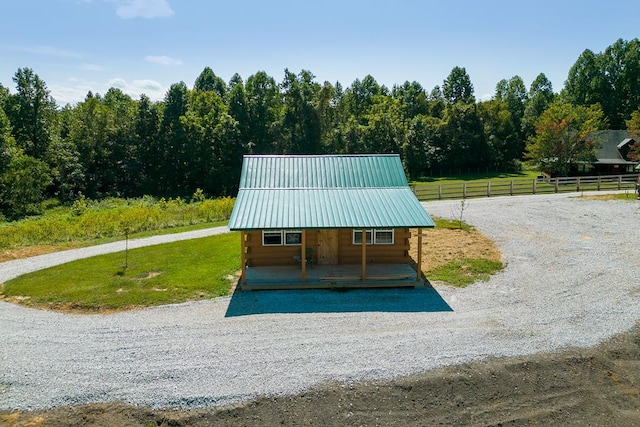 view of property's community featuring driveway, fence, a lawn, and a rural view