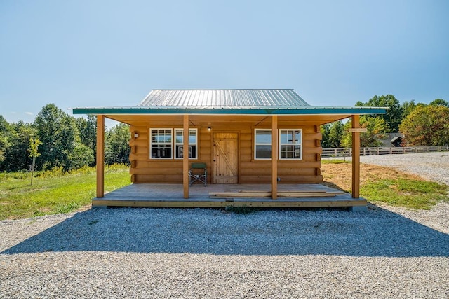 view of front of property with metal roof, log exterior, and fence