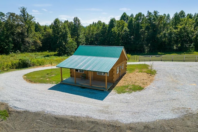 exterior space with gravel driveway, covered porch, fence, and a rural view