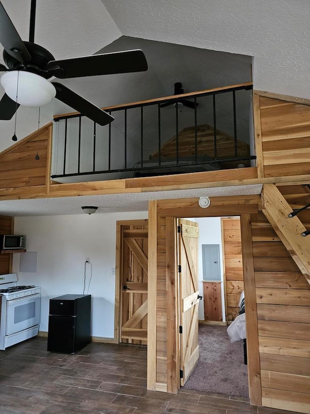 stairway featuring high vaulted ceiling, wood walls, wood finished floors, and a ceiling fan