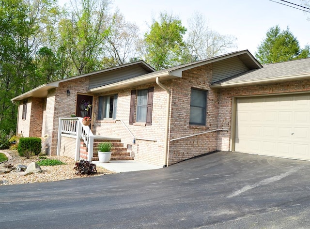 single story home with brick siding, driveway, and an attached garage