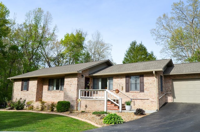 ranch-style home featuring aphalt driveway, a garage, brick siding, a shingled roof, and a front yard