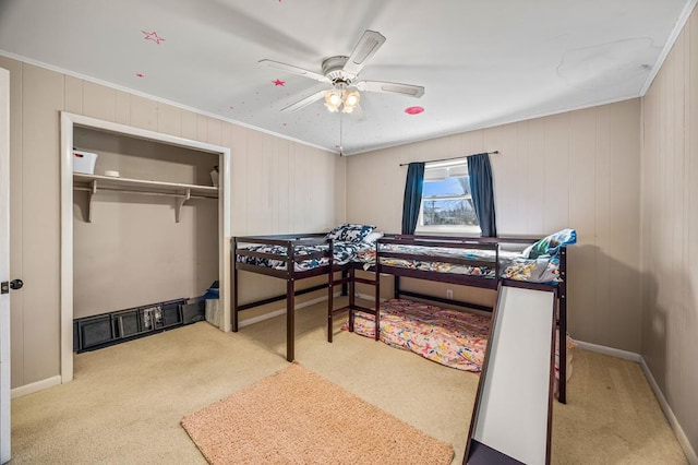 carpeted bedroom featuring a ceiling fan, ornamental molding, and a closet