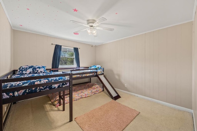 carpeted bedroom featuring a ceiling fan, crown molding, and baseboards