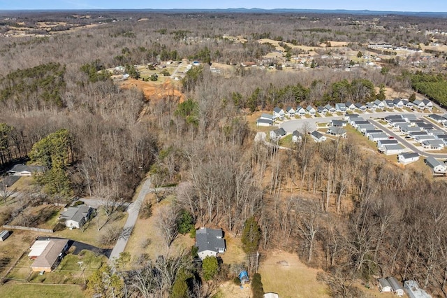 drone / aerial view featuring a wooded view and a residential view