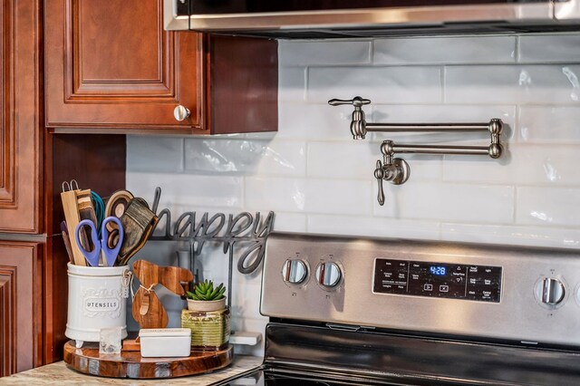 room details with under cabinet range hood, stainless steel electric stove, light countertops, brown cabinets, and tasteful backsplash