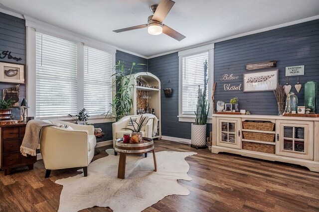 sitting room with ceiling fan, ornamental molding, dark wood finished floors, and baseboards