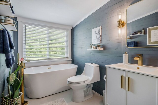 full bathroom featuring toilet, a freestanding tub, ornamental molding, and vanity