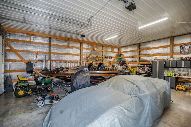 garage with a garage door opener, metal wall, and a workshop area