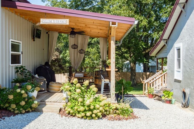 view of patio / terrace featuring driveway, a ceiling fan, an outdoor bar, fence, and a deck