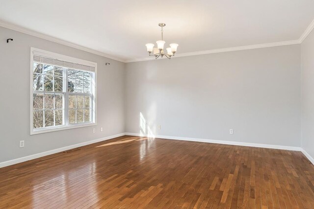 unfurnished room with a notable chandelier, wood finished floors, visible vents, baseboards, and ornamental molding