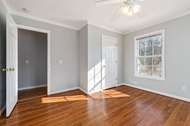 unfurnished bedroom with a ceiling fan, crown molding, baseboards, and wood finished floors