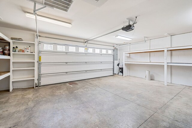 garage with electric panel, visible vents, and a garage door opener