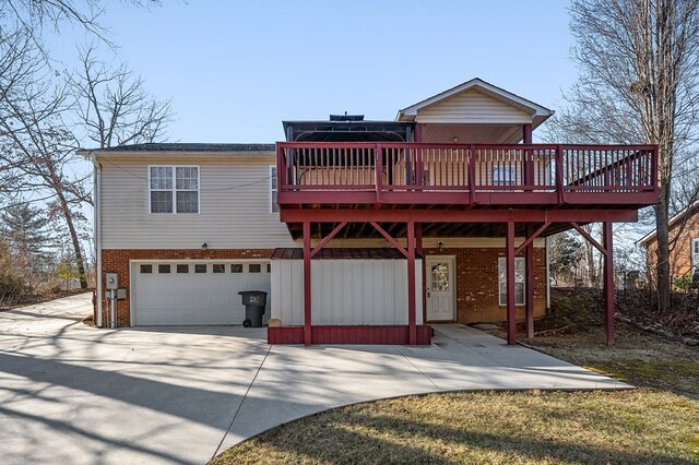 view of front of home with a garage, concrete driveway, brick siding, and a deck