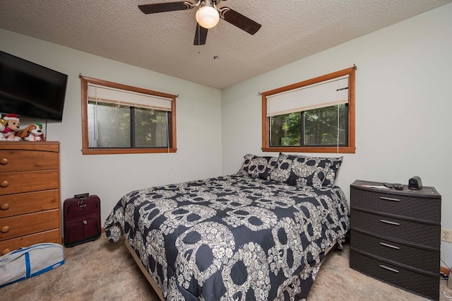 bedroom featuring light colored carpet, ceiling fan, and a textured ceiling