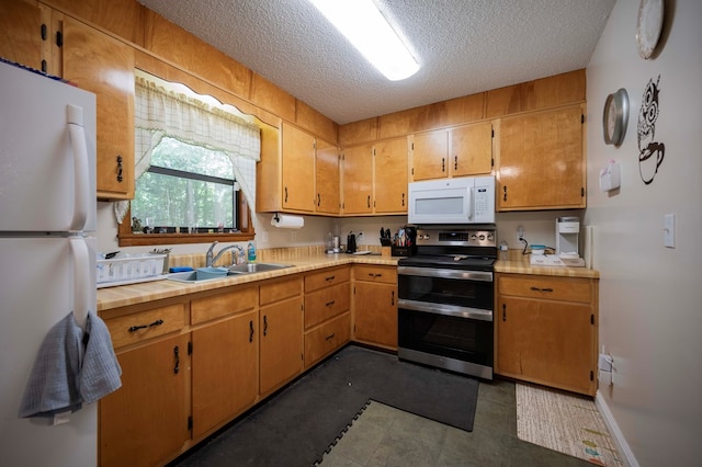 kitchen featuring white appliances, baseboards, light countertops, a textured ceiling, and a sink