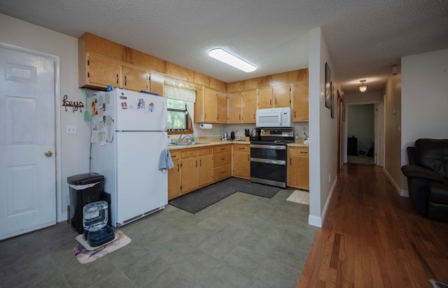 kitchen with white appliances, light countertops, a sink, and a textured ceiling