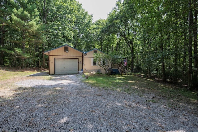 view of front facade featuring driveway, a garage, and a wooded view