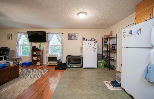 interior space featuring light wood-type flooring, freestanding refrigerator, and a textured ceiling