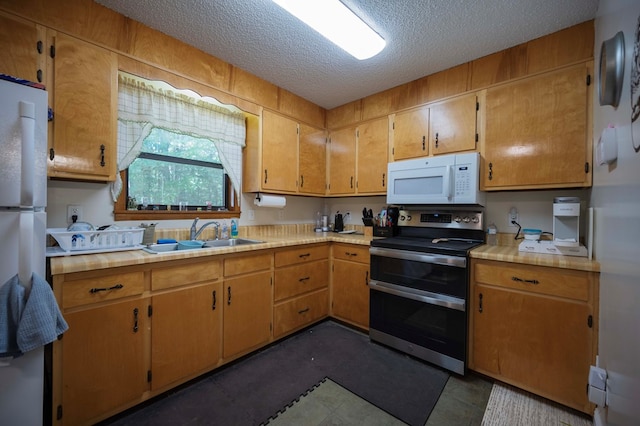 kitchen with a textured ceiling, light countertops, white appliances, and a sink