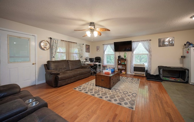 living area with ceiling fan, a textured ceiling, and wood finished floors