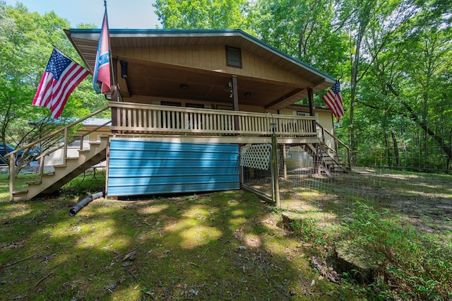 rear view of property featuring stairs and a wooden deck