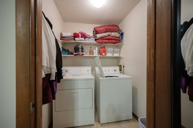 clothes washing area featuring a textured ceiling, light tile patterned flooring, and washing machine and dryer