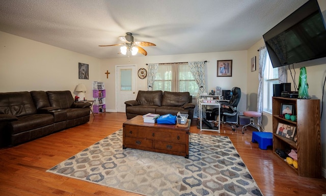 living room with a textured ceiling, ceiling fan, and wood finished floors