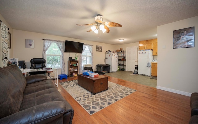 living area with baseboards, a textured ceiling, a ceiling fan, and wood finished floors